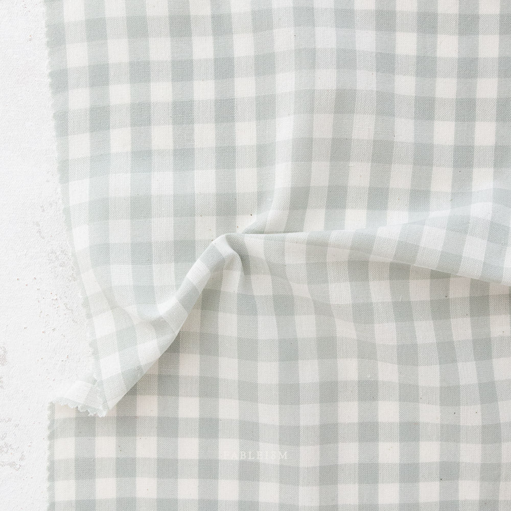 close up of white and light green/grey gingham fabric from the brand "fableism"