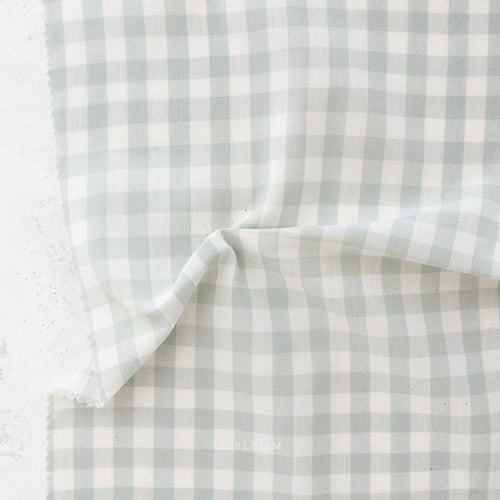 close up of white and light green/grey gingham fabric from the brand "fableism"