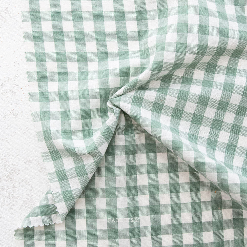 close up of white and sage green gingham fabric from the brand "fableism"
